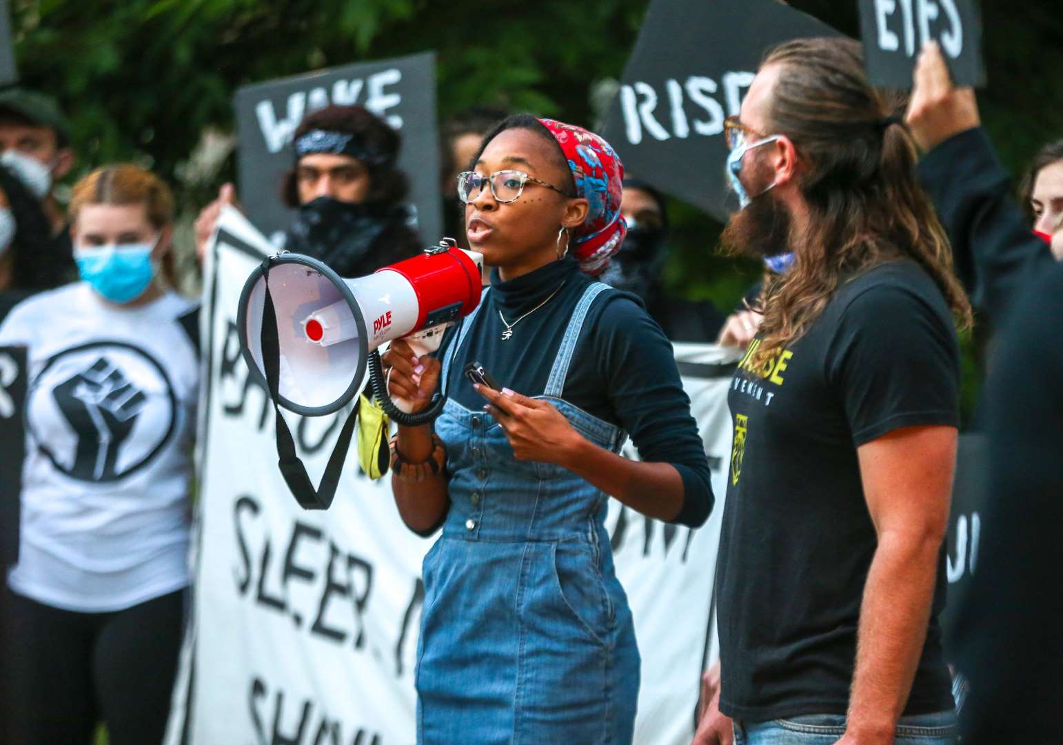 A Sunrise activist speaks into a megaphone while fellow protesters stand behind with signs.