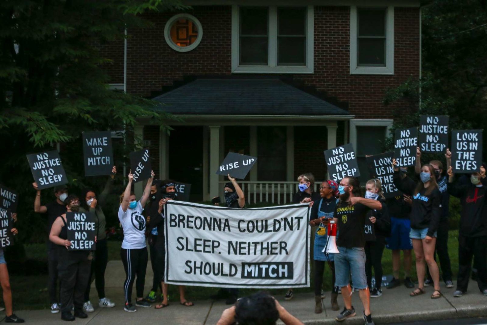 Des militants de Sunrise manifestent devant la maison de Mitch McConnell à KY, tenant une grande pancarte disant "Breonna ne pouvait pas dormir. Mitch non plus ne devrait".