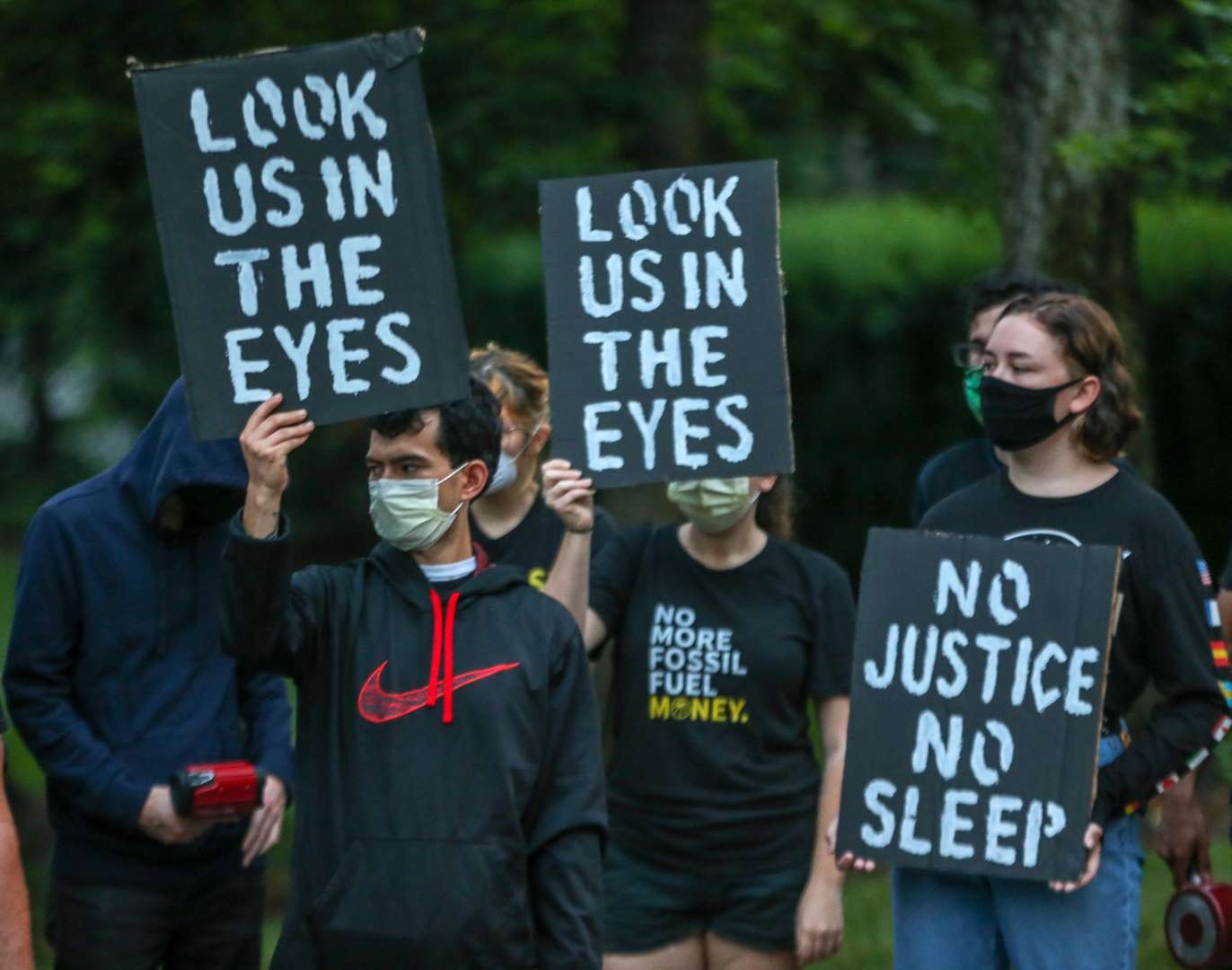 Los manifestantes sostienen carteles que dicen "No hay justicia, no hay sueño" y "Míranos a los ojos".