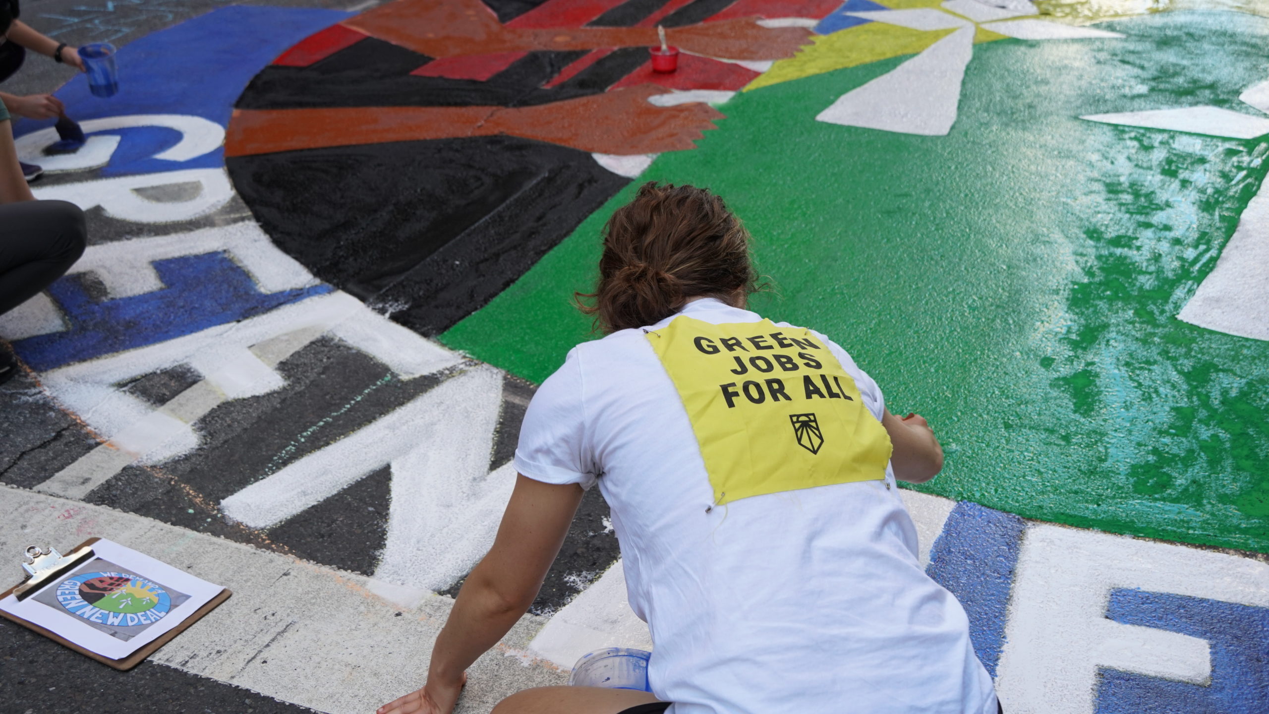 Een activist helpt bij het schilderen van een vloermuur van de Green New Deal tijdens de Klimaatstaking van september 2019.