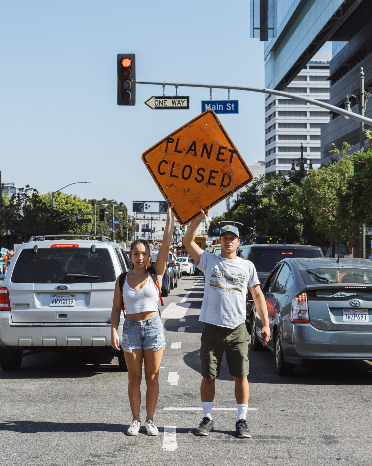 Duas pessoas seguram uma placa dizendo "Planeta Fechado" no meio da rua.