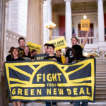 a group of people in Sunrise shirts holding a banner reading "Fight for Green New Deal"