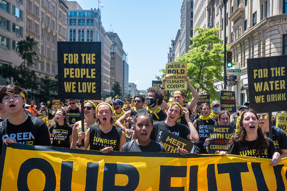 Sunrisers marching in the streets in DC with signs that read For the People We Love and For the Water We Drink