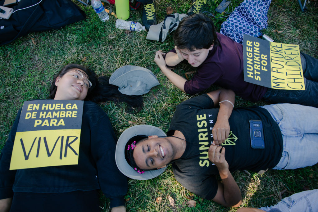 Drie activisten liggen samen op het gras.